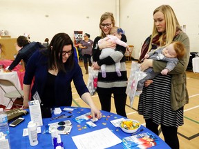 Andrea Calvert of the Belleville-based Lice Squad business talks with mothers Patricia Kouperus, centre, of Brighton and Olivia Devries of Trenton at the Mom Event Saturday at Trenton Christian School. Kouperus holds her daughter, Jade, while Devries holds her own daughter, Shae.