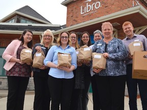 Staff at Libro Credit Union in St. Thomas hold their brown paper lunches, purchased as part of the annual Eat 2 Learn fundraiser. Money raised through the brown paper bag lunches distributed Wednesday will go toward providing students with healthy snacks and lunches throughout the school year. (Louis Pin/Times-Journal)