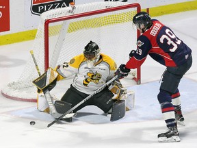 Windsor Spitfires' Curtis Douglas, right, uses his long reach against Sarnia Sting goaltender Justin Fazio in Game 4 of their OHL Western Conference quarter-final at the WFCU Centre in Windsor, Ont., on Thursday, March 29, 2018. (NICK BRANCACCIO/Postmedia Network)