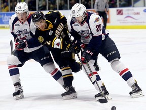 Sarnia Sting's Jonathan Ang (12) battles Windsor Spitfires' Zach Shankar, left, and Luke Kutkevicius in the first period during Game 5 in their OHL Western Conference quarter-final at Progressive Auto Sales Arena in Sarnia, Ont., on Friday, March 30, 2018. (MARK MALONE/Postmedia Network)