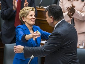 Ontario Finance Minister Charles Sousa and Ontario Premier Kathleen Wynne embrace after he delivered the provincial budget in at the Ontario Legislature in Toronto, Wednesday. Ernest Doroszuk/Postmedia Network