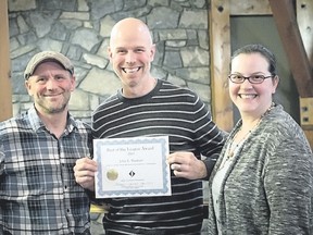 Photographer John E. Marriott, centre, holds the Best of the League award, given by League Magazine founders Darwin Wiggett, left, and Samantha Chrysanthou, right. Supplied