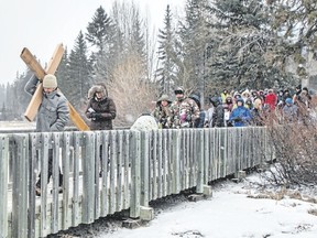 Adelio Santiago, from Canmore, carries the cross over the Policeman’s Creek boardwalk as a group of Christians follow in a snow storm during the Outdoor Way of the Cross ecumenical walk in Canmore  on Good Friday. Pam Doyle/ pamdoylephoto.com