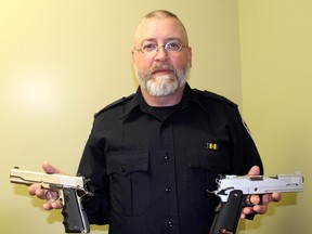 To illustrate the sophistication of today's replica weapons, Const. Robert Tobin, firearms examiner for the Chatham-Kent Police Service, displays a real Model 1911 U.S. Army .45-calibre pistol, left, and a WEI - Etech replica .45-caliber pistol, right. Ellwood Shreve/Postmedia Network