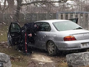 A Kingston Police officer peers into a unregistered and uninsured vehicle after arresting its driver off Daly Street in Kingston, Ont. on Wednesday April 4, 2018. Supplied by Kingston Police