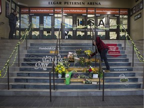 A man drops of flowers at a memorial located inside the Elgar Petersen Arena in Humboldt, SK on Saturday, April 7, 2018. (Saskatoon StarPhoenix/Kayle Neis)