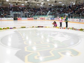 People lay flowers during a vigil at the Elgar Petersen Arena, home of the Humboldt Broncos, to honour the victims of a fatal bus accident in Humboldt, Sask. on Sunday, April 8, 2018. THE CANADIAN PRESS/Jonathan Hayward