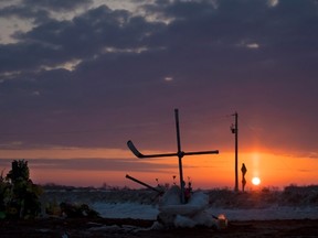 The sun rises across the Prairies on Tuesday morning as a cross made out of hockey sticks is seen at a makeshift memorial at the intersection where a fatal bus crash took place on Friday night near Tisdale, Sask. A bus carrying the Humboldt Broncos junior hockey team to a game in Nipawin collided with a tractor-trailer, killing 15 members of the organization and sending more than a dozen more to the hospital. THE CANADIAN PRESS/Jonathan Hayward