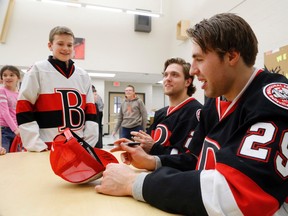 LUKE HENDRY/THE INTELLIGENCER
Ethan Werek, right, of the Belleville Senators signs Harmony Public School student Owen Bird's hat while sitting with teammate Macoy Erkamps Wednesday in the library of the school in Belleville. Students in the Grade 3/4 and Grade 7 classes worked together to create mascot concepts, then showed them to the players.