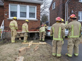Firefighters shore up the foundation of a house on Alfred Street after it was damaged when a car overshot the intersection with Concession Street in Kingston, Ont. on Thursday, April 12, 2018.