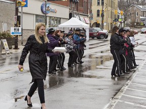 Andrea Ferrier, a financial advisor at TD Canada Trust, carries a take-out order of pancakes to the bank while the Waistliners line dancing group perform a number during the Paris Lions Club's annual Maple Syrup Festival on Saturday in downtown Paris.
Brian Thompson/The Expositor