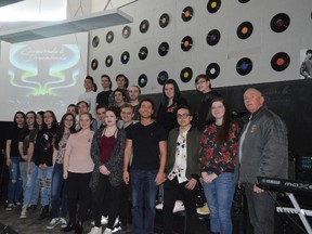 Sonic Democracy band members, pictured here with teacher Barry Promane, centre, and Tahoe Resources’ Tom Laughren, are working on the songs for their latest album, Crossroads & Dreamlands. The cover art is projected above them. The Timmins High & Vocational School band is headed to Toronto in May to record their five-song concept album.