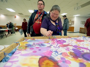 Jaimie Tremblay adds to the painted silk that was created collectively by attendees at Get Connected, a community mental health awareness event in Napanee on Friday. (Meghan Balogh/The Whig-Standard/Postmedia Network)