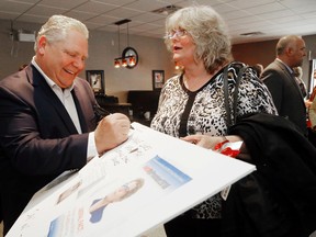 Luke Hendry/The Intelligencer
Ontario Progressive Conservative party leader Doug Ford signs an anti-Liberal sign made by Janine LeClerc of Trenton Wednesday, April 18, 2018 in Belleville, Ont. LeClerc said she likes Ford because "he's for free speech" and currently "nobody has any right to free speech except for Islamic people." Ford held a meet-and-greet session at The Dugout restaurant before opening the Trenton campaign office of Bay of Quinte PC candidate Todd Smith, background.