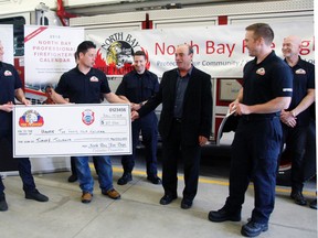 North Bay firefighters present a $20,000 cheque to Paul Laperriere, director of corporate services at Hands the Family Network Wednesday.