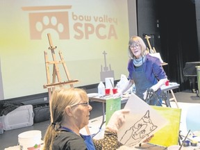 Barbara Bertsch (left) holds her outline as local artist and painting instructor Wanda Ellerbeck teaches a painting class at the Paws ’N Paints fundraiser for the Bow Valley SPCA at artsPlace on April 8. Pam Doyle/ pamdoylephoto.com