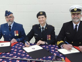 Photo by KELLY JAMES/FOR THE STANDARD
Lt. Dennis Meeking (left) signs the paperwork making him the new commanding officer of the 696 Royal Canadian Air Cadet Squadron in Blind River. Joining Meeking for the ceremony are presiding officer Major Pascale Crepault-Breckenridge (centre) and out-going commanding officer Lt. Commander Robert Pihlaja.