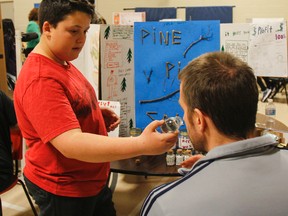 Jake Perry, a Grade 7 student, offers one of the judges a smell of his Pine Pitch Salve, a product he developed for the KidPreneur Fair at J.J. O'Neill Catholic School in Napanee on Tuesday. (Julia McKay/The Whig-Standard)