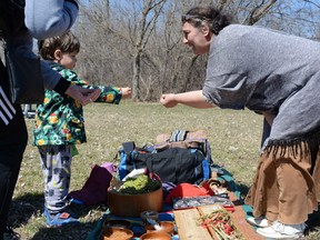 Lisa Cadue from the Mohawk Tyendinaga territory hands Henrik Sarmazian a special item to throw into a ceremonial fire at Belle Park on Earth Day, on Sunday.