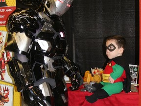Five-year-old Robin Fortier, fittingly suited up as Batman's sidekick Robin, gets a close-up view of Brampton Ironman's suit Saturday in the Cosplay Corner of the Comicon Timmins event held at the McIntyre Curling Rink this weekend.