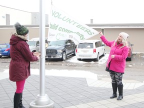 KASSIDY CHRISTENSEN HIGH RIVER TIMES/POSTMEDIA NETWORK. Jennifer Hogan, legislative and policy coordinator with the town, left, and Jody Seeley, community engagement orchestrator with Our High River, right, raised the volunteer flag outside the High River Municipal Building on April 16 in celebration of National Volunteer Week, which runs April 15 to 21. Town officials said the flag will be flown all week.