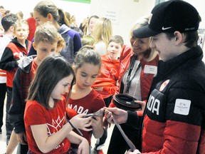 Addison Schoonderwoerd  (left) and Zoey Michel, students of St. Columban School in St. Columban, take a quick look last Wednesday, April 18 at the silver medal won by Corbyn Smith, of Monkton, as a member of the Canadian Paralympic sledge hockey team in South Korea last month. Smith, 19, was a special guest of both St. Columban and St. Patrick’s School in Dublin as he has relatives that attend St. Patrick’s. ANDY BADER/MITCHELL ADVOCATE