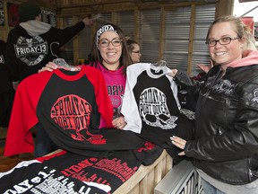Alexis DeGroote (left) of Dave's World shows some Friday the 13th T-shirts to Leah Warren of Wasaga Beach during the Friday the 13th motorcycle rally on April 13  in Port Dover. Brian Thompson/Postmedia News