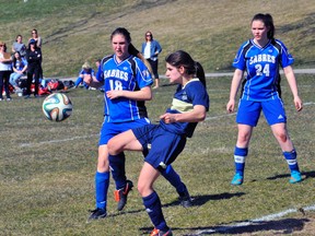 Delhi defender Hannah Ferrell looks to clear the ball while being guarded by Hope Lesage and Hanna Patrick of SCS during the NSSAA girls soccer opener on Monday in Simcoe. Patrick scored the only goal of the contest, earning Simcoe a 1-0 victory. JACOB ROBINSON/Simcoe Reformer