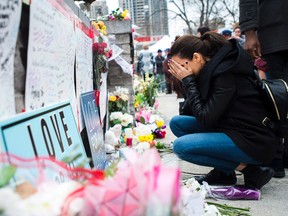 A woman fights back tears Tuesday at a memorial for the victims along Yonge Street in Toronto, the day after a driver drove a rented van down sidewalks Monday afternoon, striking pedestrians in his path. THE CANADIAN PRESS/Nathan Denette