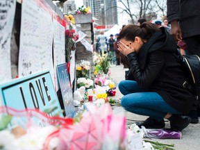A woman fights back tears Tuesday at a memorial for the victims along Yonge Street in Toronto, the day after a driver drove a rented van down sidewalks striking pedestrians in his path. THE CANADIAN PRESS/Nathan Denette