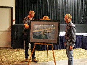 Henry Vos stands beside the Brian Hohner painting of the Canso that he commissioned for the Save the Canso group. Hohner is at left behind the painting. Prints of the painting will be sold as a fundraiser for the Canso.