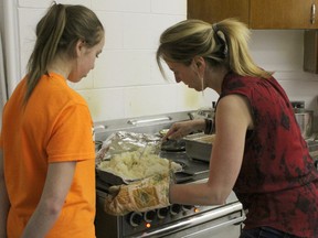 Opening Our Doors volunteers Chloe Herr (left) and her mother Leslie Herr prepare a tray of mashed potatoes for the program's last meal service at Knox United Church on Wednesday, April 25. The section of the Knox building that will house the new permanent emergency shelter is expected to start renovations soon.
KATHLEEN CHARLEBOIS/DAILY MINER AND NEWS
