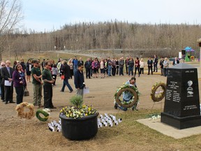 People lay flowers at a cenotaph at J. Howard Pew Park as part of the National Day of Mourning ceremony in Fort McMurray, Alta. on Saturday, April 28, 2018. Vincent McDermott/Fort McMurray Today/Postmedia Network