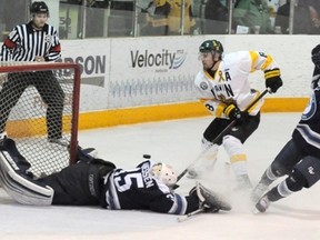 The Hawk's Brett Harasymuk looks on as Matthew Thiessen hits the ice after pulling the puck out from under Harasymuk's stick.