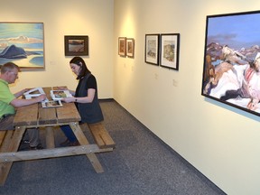 David Huff, acting director, and Heather McLeese, curator, at the Tom Thomson Art Gallery, leaf through books of artwork in the exhibition Trailblazers: Tom Thomson and the Group of Seven in Ontario's Provincial Parks on Thursday, May 3, 2018 in Owen Sound, Ont. The show highlights the works of Thomson, the Group of Seven and those artists who came after. At right is the La Cloche Mountains by artist John Hartman, representing Killarney Provincial Park. while at left is Pic Island by Lauren Harris representing Neys Provincial Park on Lake Superior. Rob Gowan/The Owen Sound Sun Times/Postmedia Network