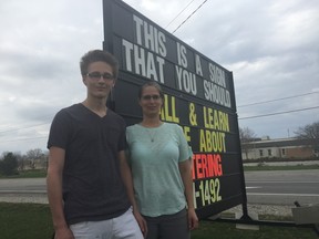 Natasha Schaafsma-Wright and her son Josh stand next to a temporary sign facing Sunset Drive in St. Thomas. Schaafsma-Wright and her husband are owners of RT-Signs, which rents temporary signs out to businesses in the city. They are upset with an updated bylaw that prohibits where and when signs can be put up. (Laura Broadley/Times-Journal)