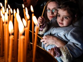 Greek Orthodox believers light candles during Good Friday's 'Apokathelosis', the lowering of Christ's dead body from the Cross, which forms a key part of Orthodox Easter, at Pendeli monastery, north of Athens, on April 6, 2018.
 Millions of Greeks flock to churches around the country this week to celebrate Easter, the country's foremost religious celebration. / AFP PHOTO / ARIS MESSINISARIS MESSINIS