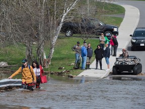 Simon Barton, left, and Chelsea Burley wear makeshift waders of garbage bags and packing tape as they cross a flooded road in Saint John, N.B., Sunday.
THE CANADIAN PRESS/Andrew Vaughan