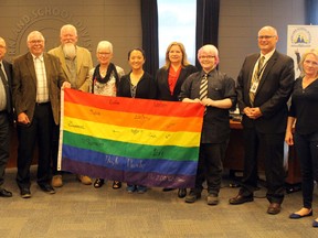 Jake Glover from the High Park school GSA presents the PSD board of trustees with a signed LGBTQ flag.