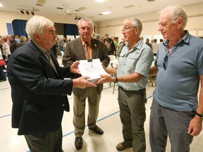 Don Scott, left, receives petitions protesting suggested NEC planning area changes from Mark Young, second right, during a public meeting on the proposed NEC plan at the Owen Sound legion in 2016.  Georgian Bluffs Mayor and Grey County Warden Alan Barfoot is second left and Vaughn Johnstone in on the right. (Sun Times file photo)  
James Masters/The Owen Sound Sun Times/