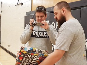 KEVIN RUSHWORTH HIGH RIVER TIMES/POSTMEDIA NETWORK. Chris Watson, right, gets some help in documenting his attempt to throw the Guinness World Records book on April 14.