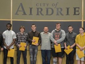 Mike Reist, organizer of the Adopt-a-Grad Program, poses with Mayor Peter Brown and some of the sponsored students on May 3. The program raised close to $7,400 to help 16 students be fitted for grad suits.