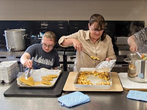 Paris Meals on Wheels volunteers Jennah Clarke (left), Nancy Dawdy and Brenda Carballo prepare a hot meal for their clients on Wednesday in the kitchen at the Paris fairgrounds. (Brian Thompson/The Expositor)