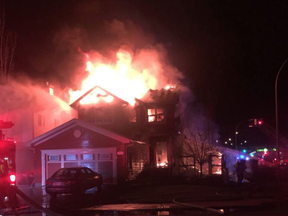 Flames erupt from the top of a home on Appleton Way, just off Cloverbar Road, as fire crews respond to a blaze that demolished a local home in Aspen Trails.