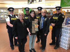Supplied Photo 
Jazmyn Maki holds a framed copy of her artwork that's featured on 125,000 bags to be distributed by LCBO. The Grade 8 student at St. Joseph French Immersion student's artwork was chosen from more than 50,000 entries to LCBO's Think of Me campaign in 2017. Maki is joined at the Wawa LCBO by, at rear, Staff Sgt. Megan Cavanagh, Const. Levis Brousseau, Const. Suzanne Lacasse and Sgt. Richard Bordin of Ontario Provincial Police and, at front, her grandmother Cindy Maki and store manager Connie Gerrior.