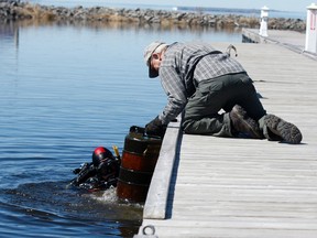 Jim Mainville hands a large pylon found on the lake bottom to Rick Taylor Sunday during a clean up of the city's marina.