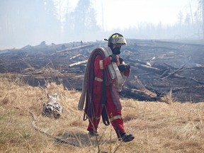 A firefighter carries equipment away from an extinguished area in Strathcona County, where grassfires raged throughout the weekend.

Jeff Labine/Postmedia Network