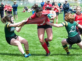 Player-coach Cindy Nelles crashes through a pair of Cobourg Saxons defenders during recent season-opening TRU senior women's rugby action at MAS Park. (Don Carr photo)