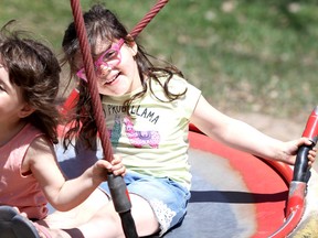 Cousins Alice McIntosh, 4, and Charlotte McDermid, 4, enjoy a ride in a saucer swing at Belleuve Park on Tuesday afternoon. Charlotte's mother, Mikaela, supplies the power.