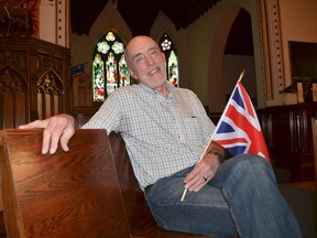 Rev. Graham Bland holds a British flag at the front of St.George's Anglican Church Tuesday, where a big screen will be set up for the community to come for scones, tea, and to watch Prince Harry and Meghan Markle's wedding starting at 6:30 a.m. Saturday. (Scott Dunn/The Sun Times)